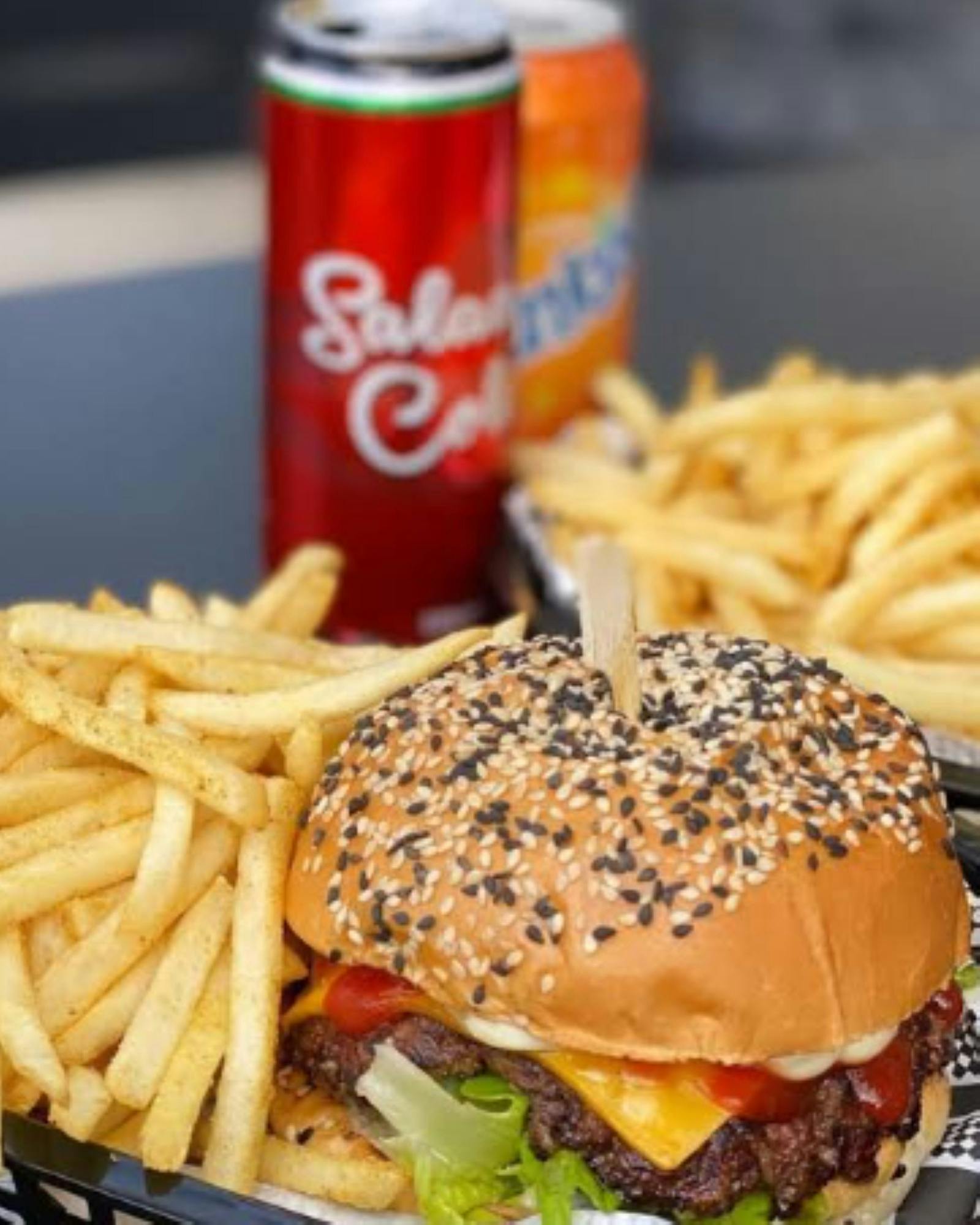 a can of drink a burger and two servings of fries on the table