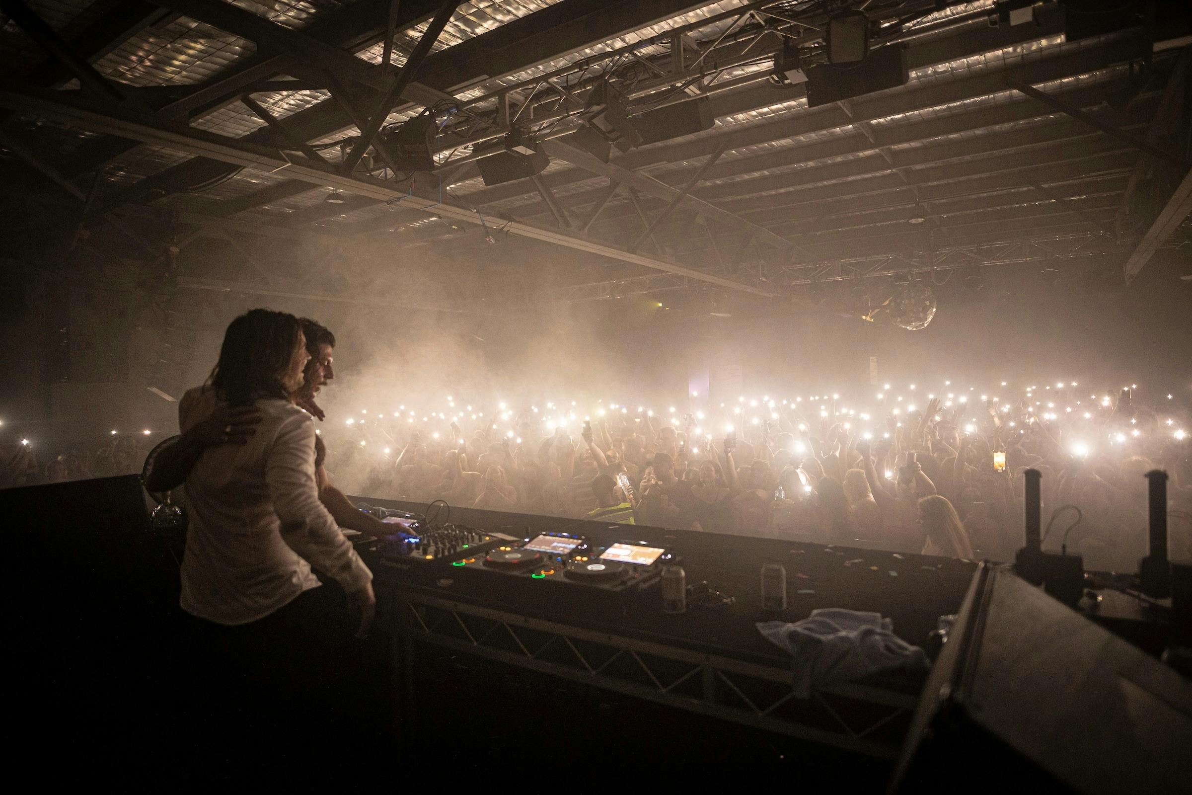 Large dance floor with hundreds of torches waving to the DJs
