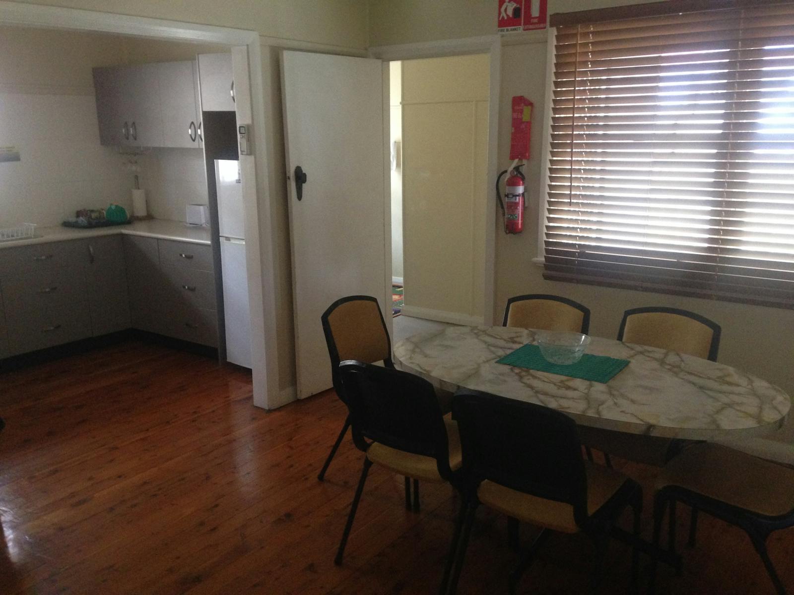 Kitchen on left with oval dinning table and six chairs on right.