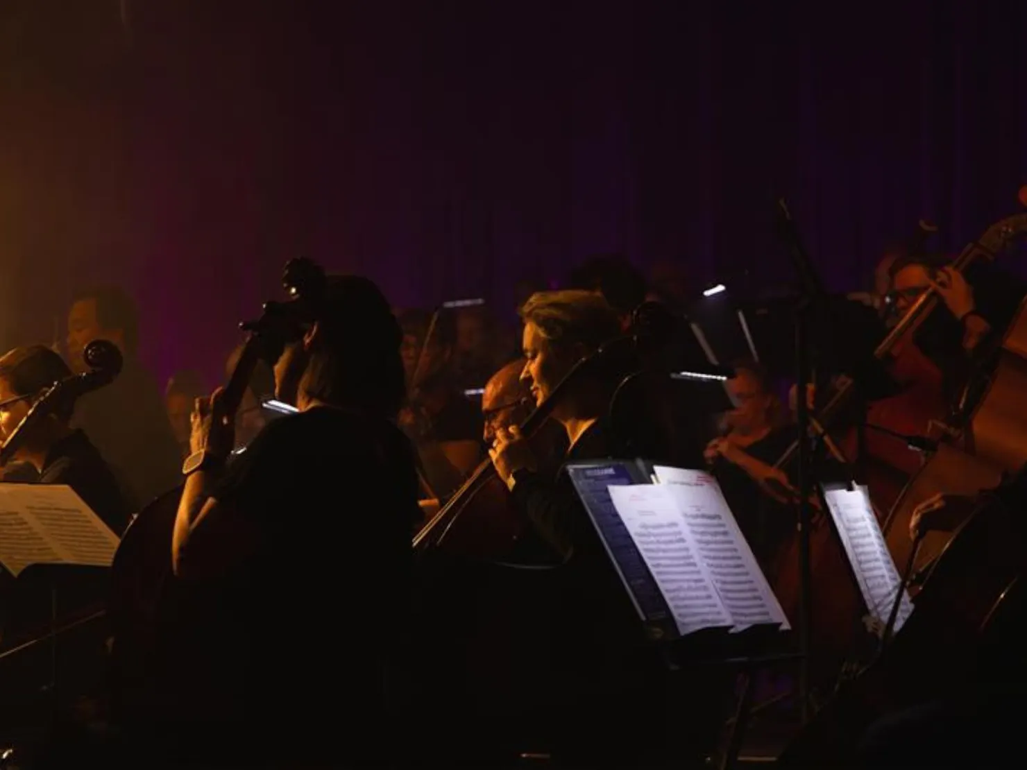 dark orchestra playing with sheet mucis in foreground
