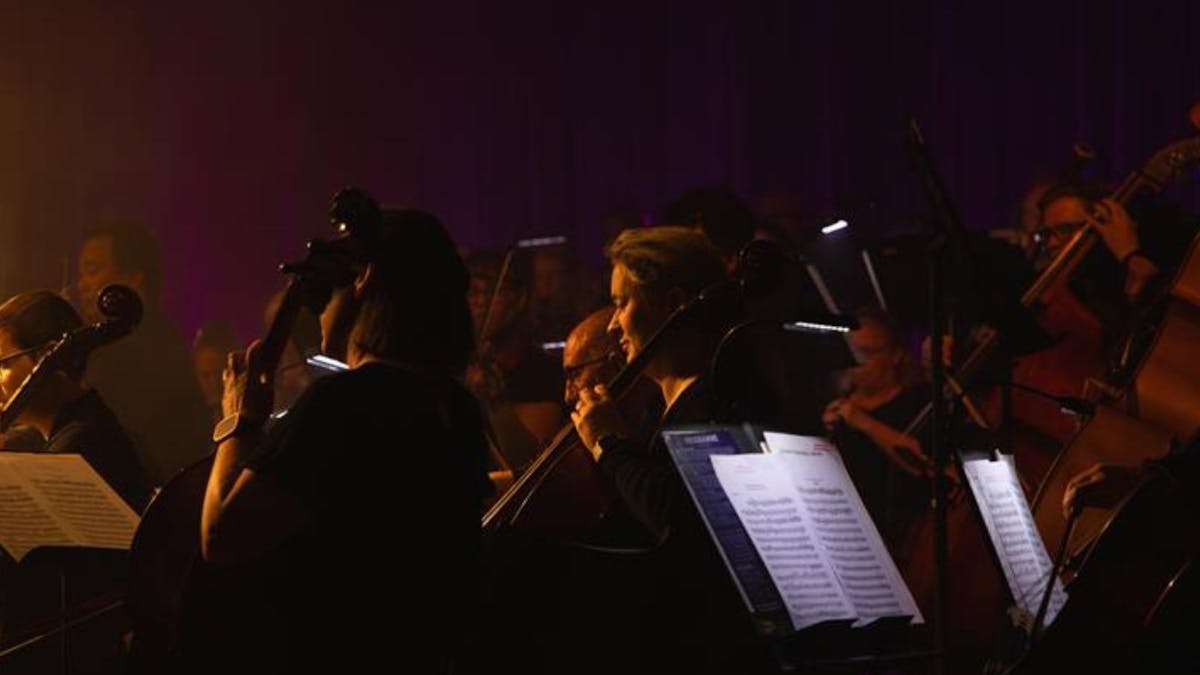dark orchestra playing with sheet mucis in foreground