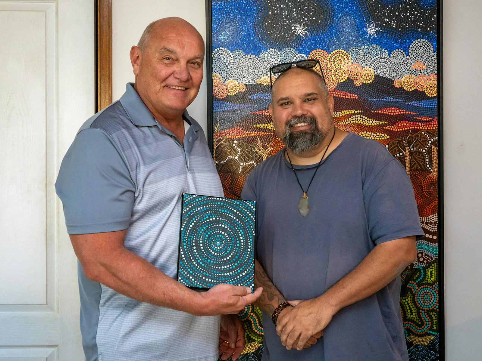 2 men, one holding painting