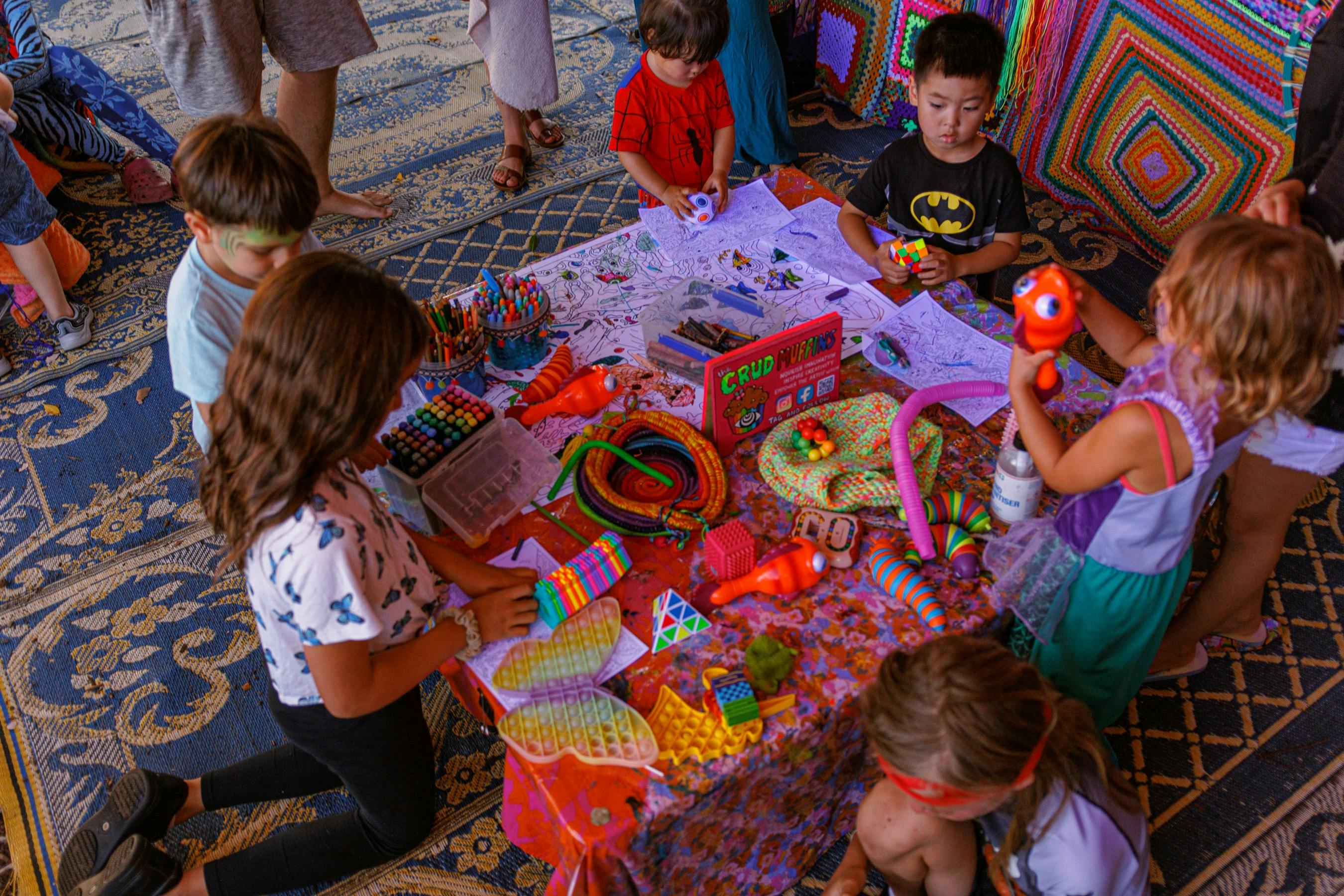 Children sitting around a table covered in neon arts and crafts