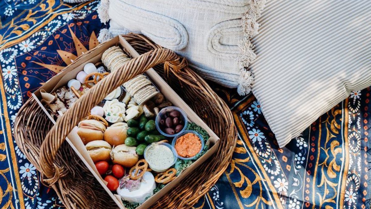 Select of picnic goods inside a wicker basket with drinks