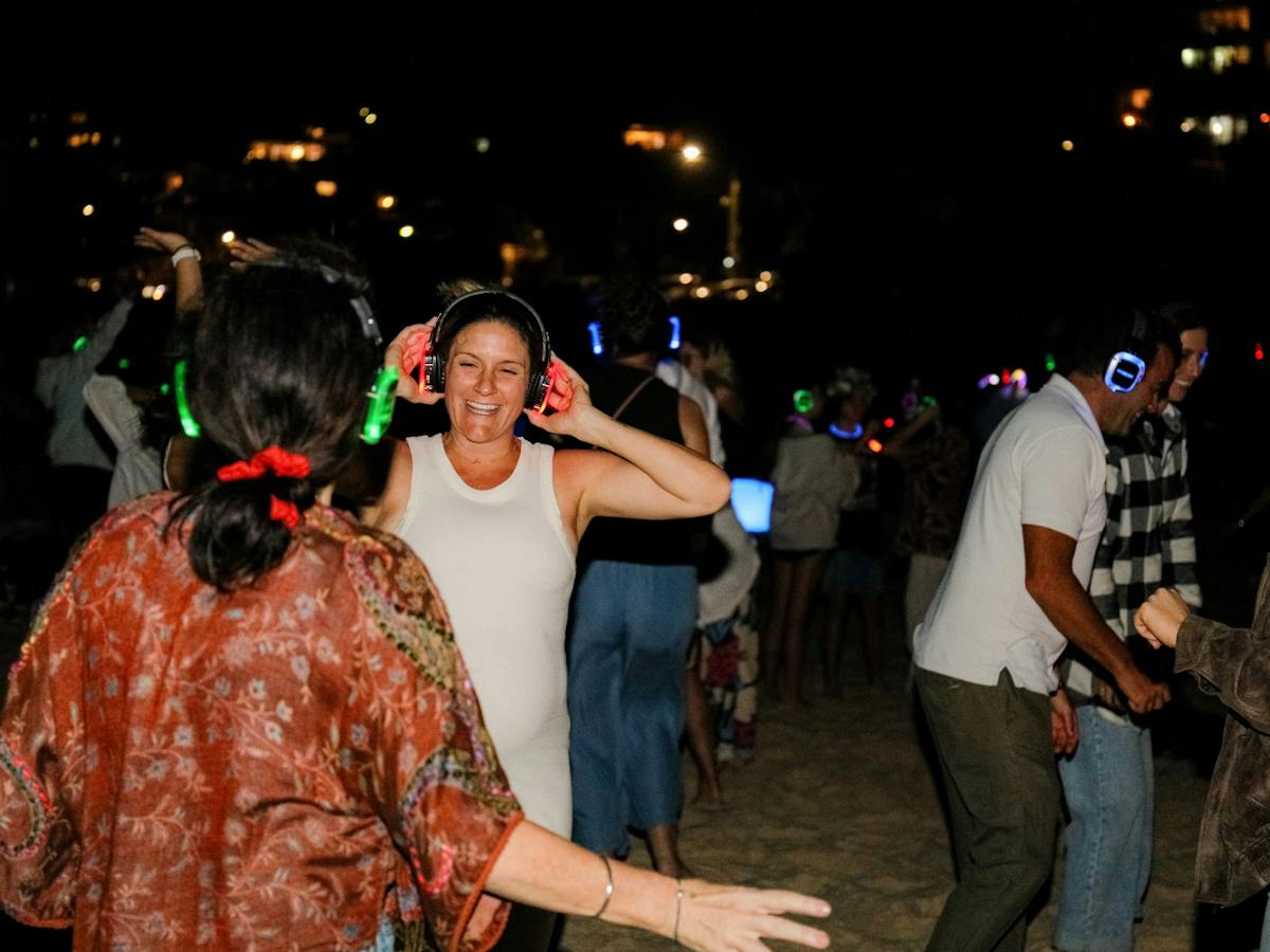 100's of people dancing on the beach atSilent Disco Under the Stars at SWELL Sculpture Festival 2024