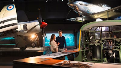 man and woman standing in galleries, surrounded by planes