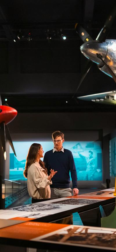 man and woman standing in galleries, surrounded by planes
