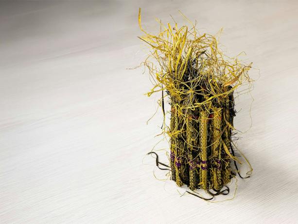 A small sculptural raffia weaving in yellow and black