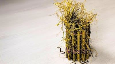 A small sculptural raffia weaving in yellow and black