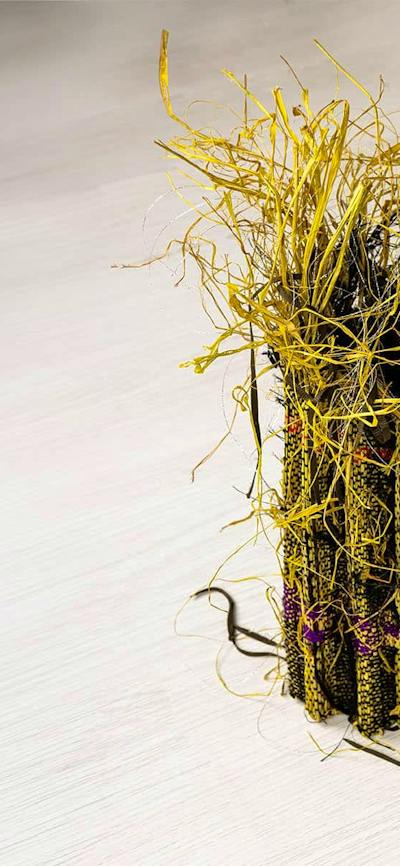A small sculptural raffia weaving in yellow and black