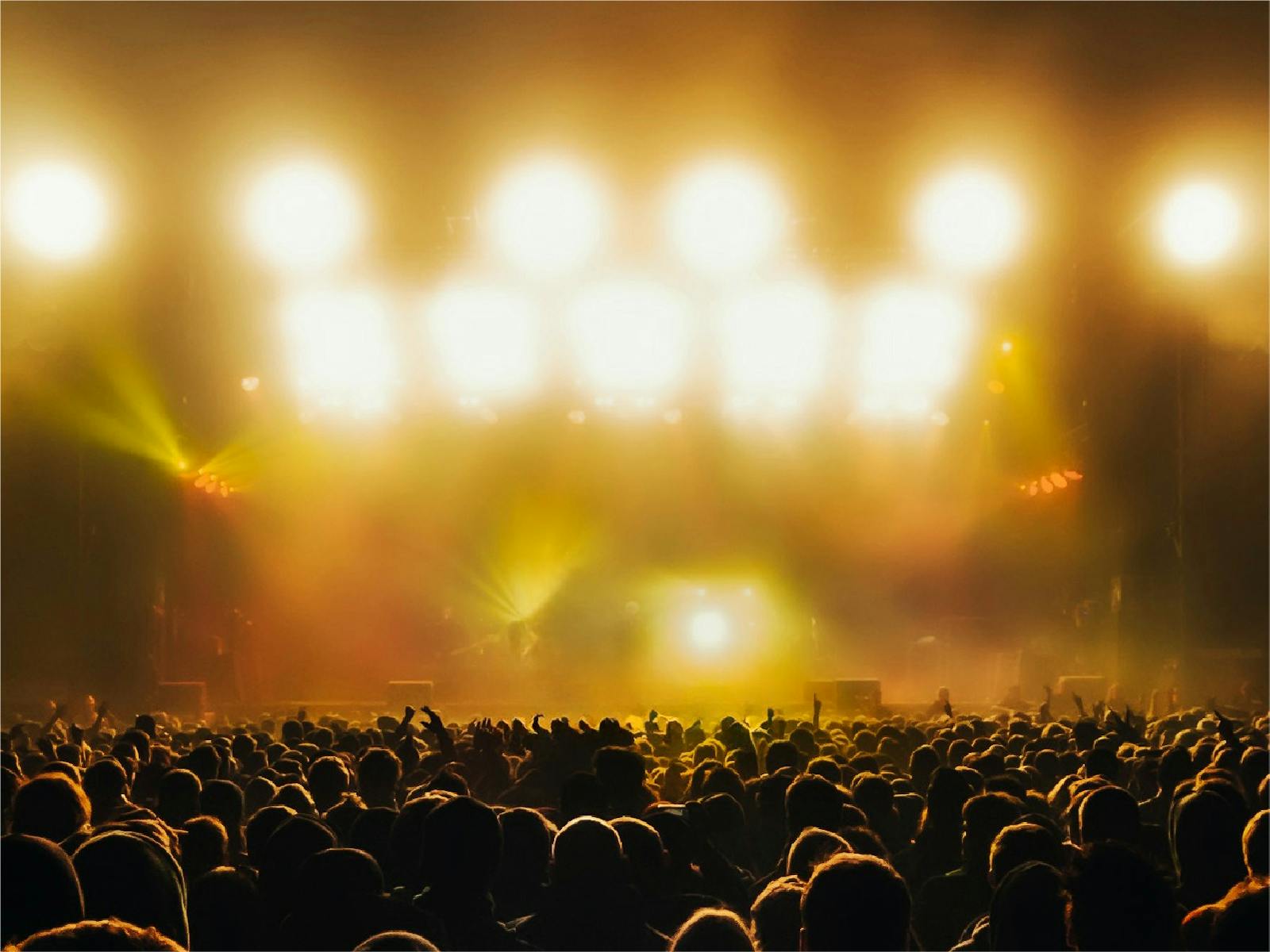 A crowd of people at a music concert, bathed in golden yellow light A crowd of people at a music concert, bathed in golden yellow light