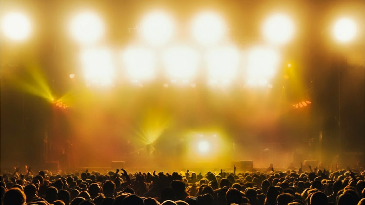 A crowd of people at a music concert, bathed in golden yellow light