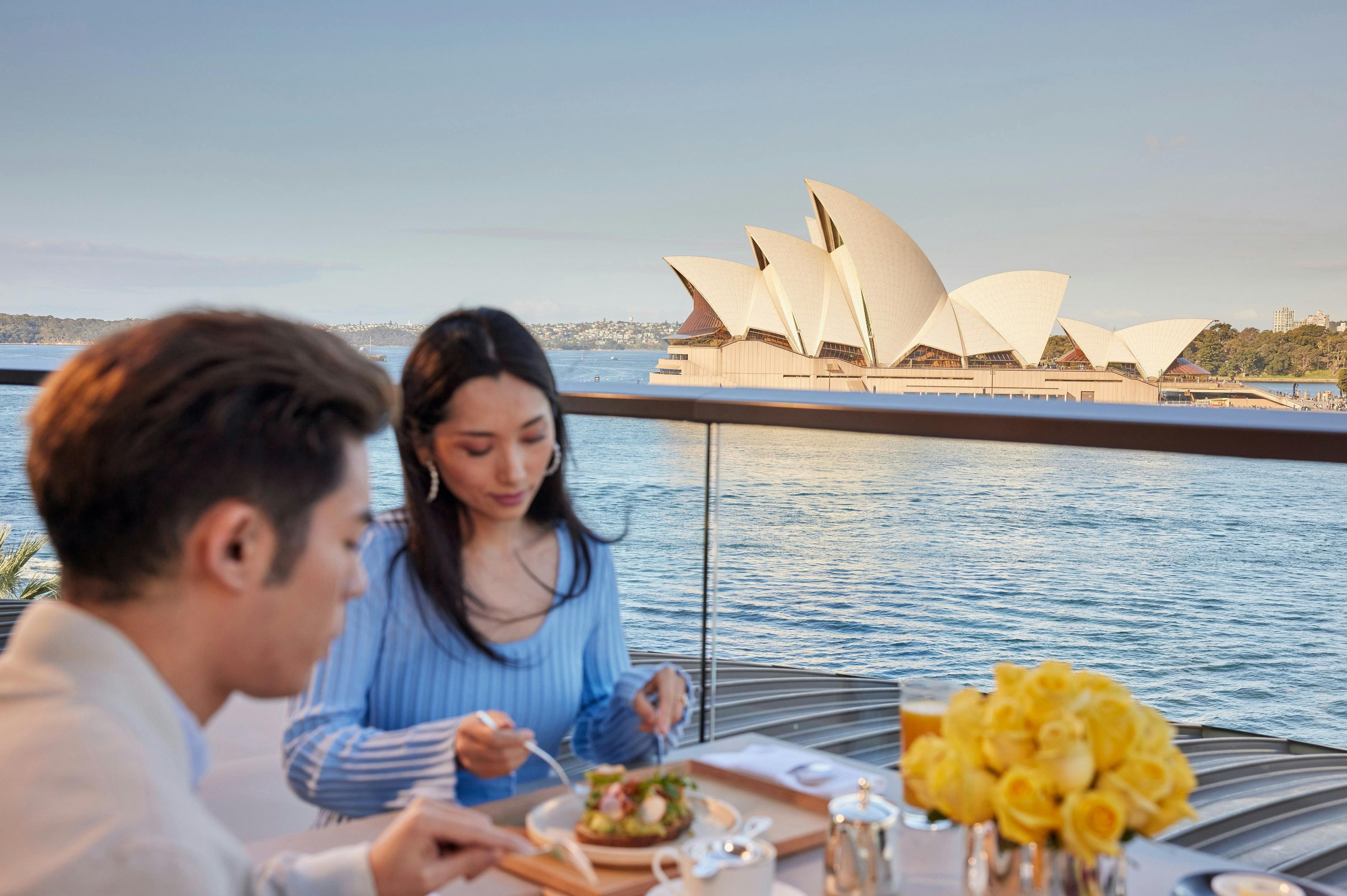 Couple enjoying a meal with iconic views of Sydney Harbour on the balcony of the Park Hyatt