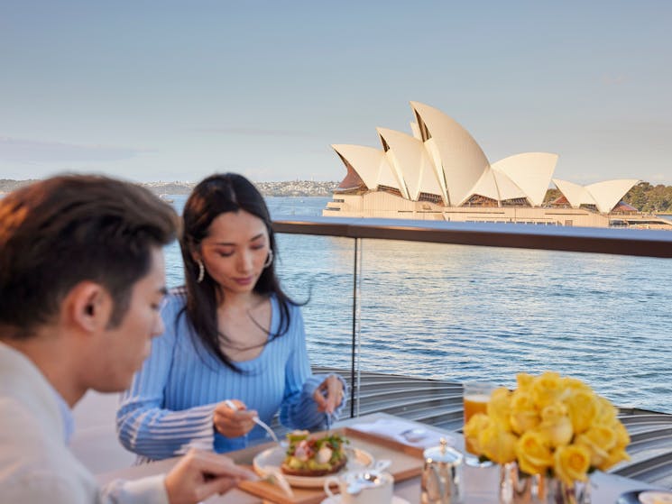 Couple enjoying a meal with iconic views of Sydney Harbour on the balcony of the Park Hyatt