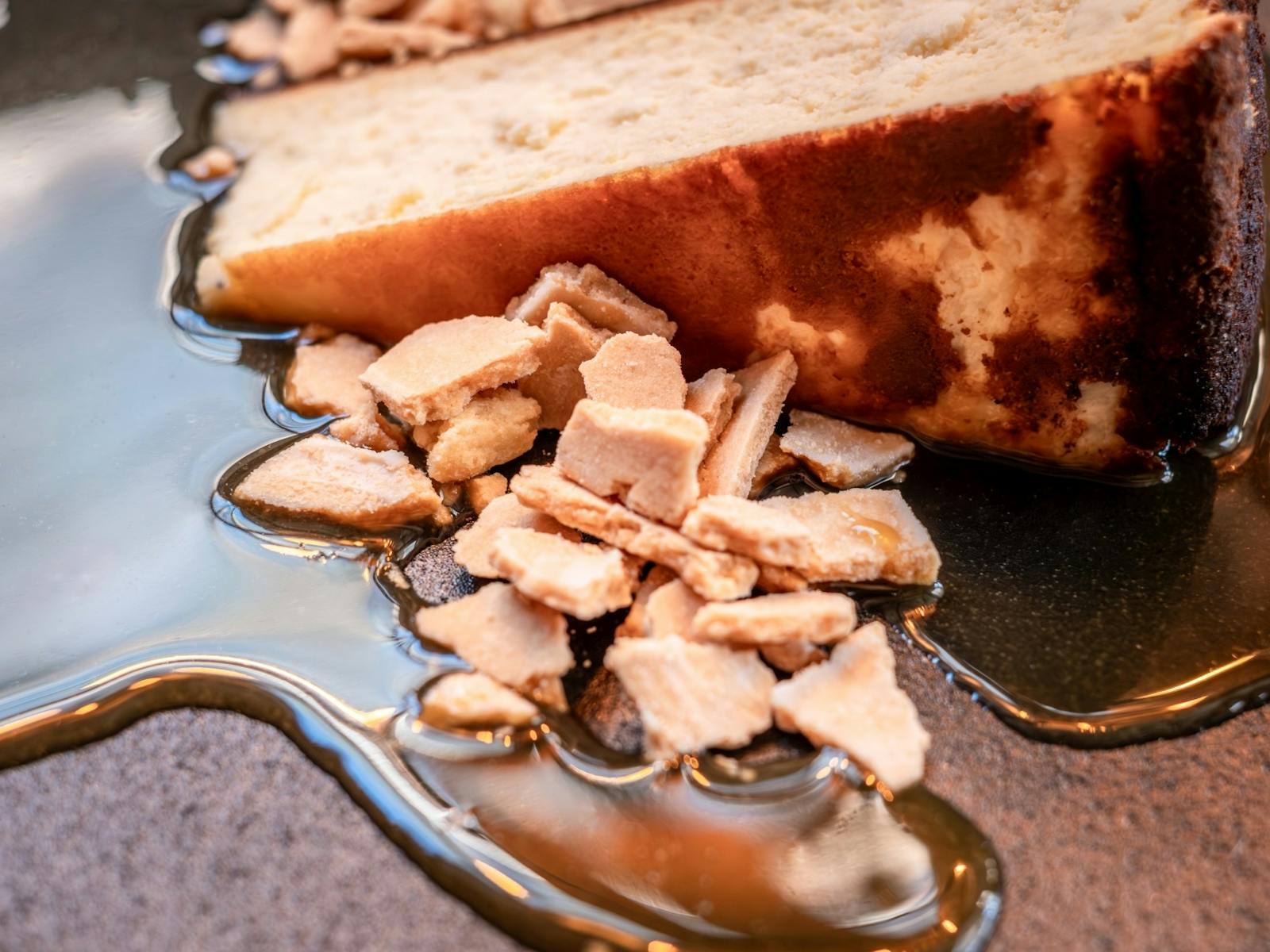 A slice of cheesecake with honeycomb crumble and a salted caramel sauce