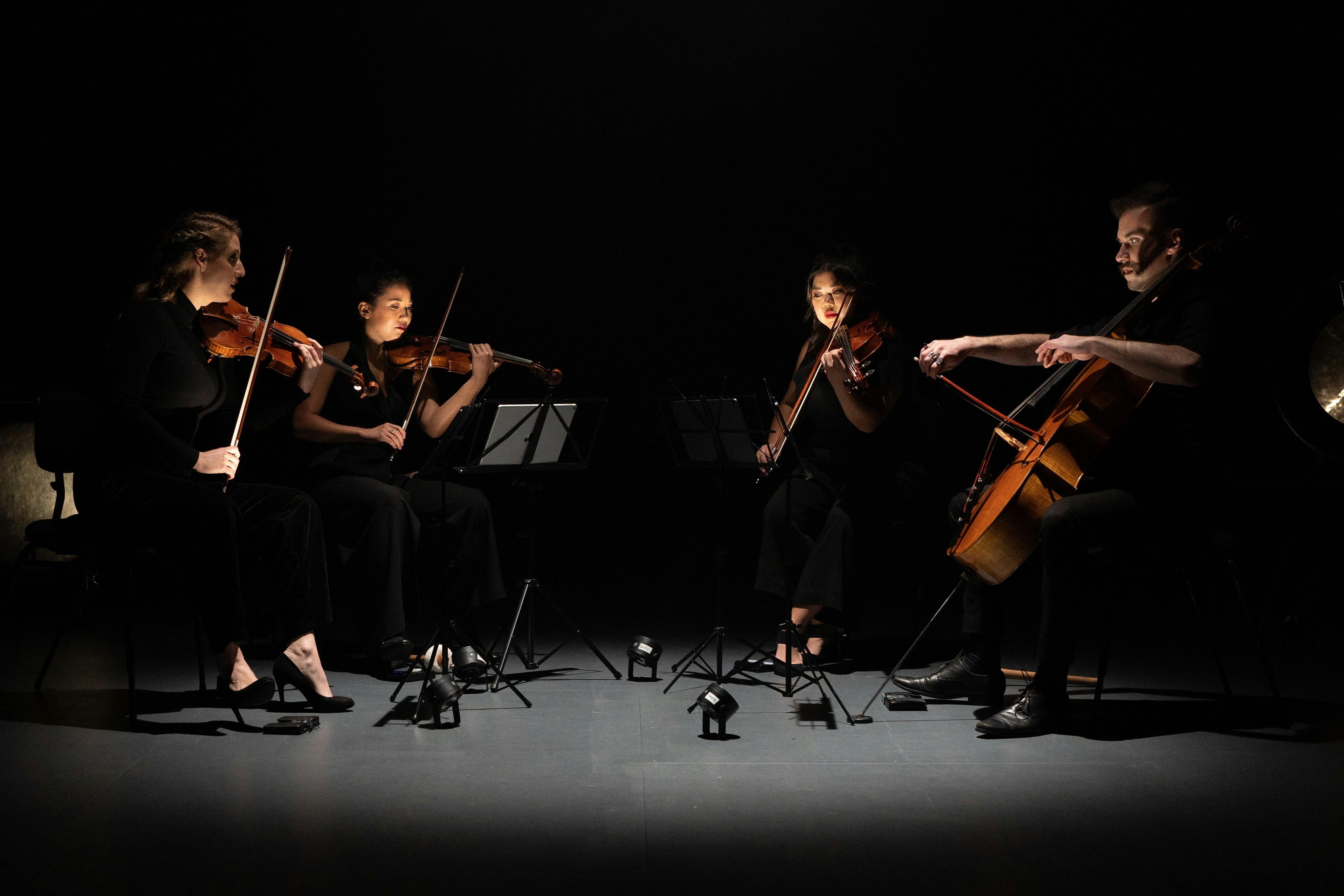 group of musicians playing their instruments in moody dark lighting