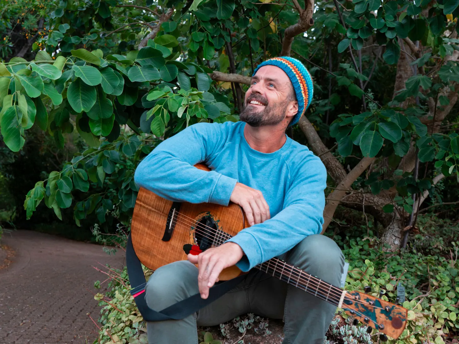 Xavier Rudd sitting down with his acoustic guitar.