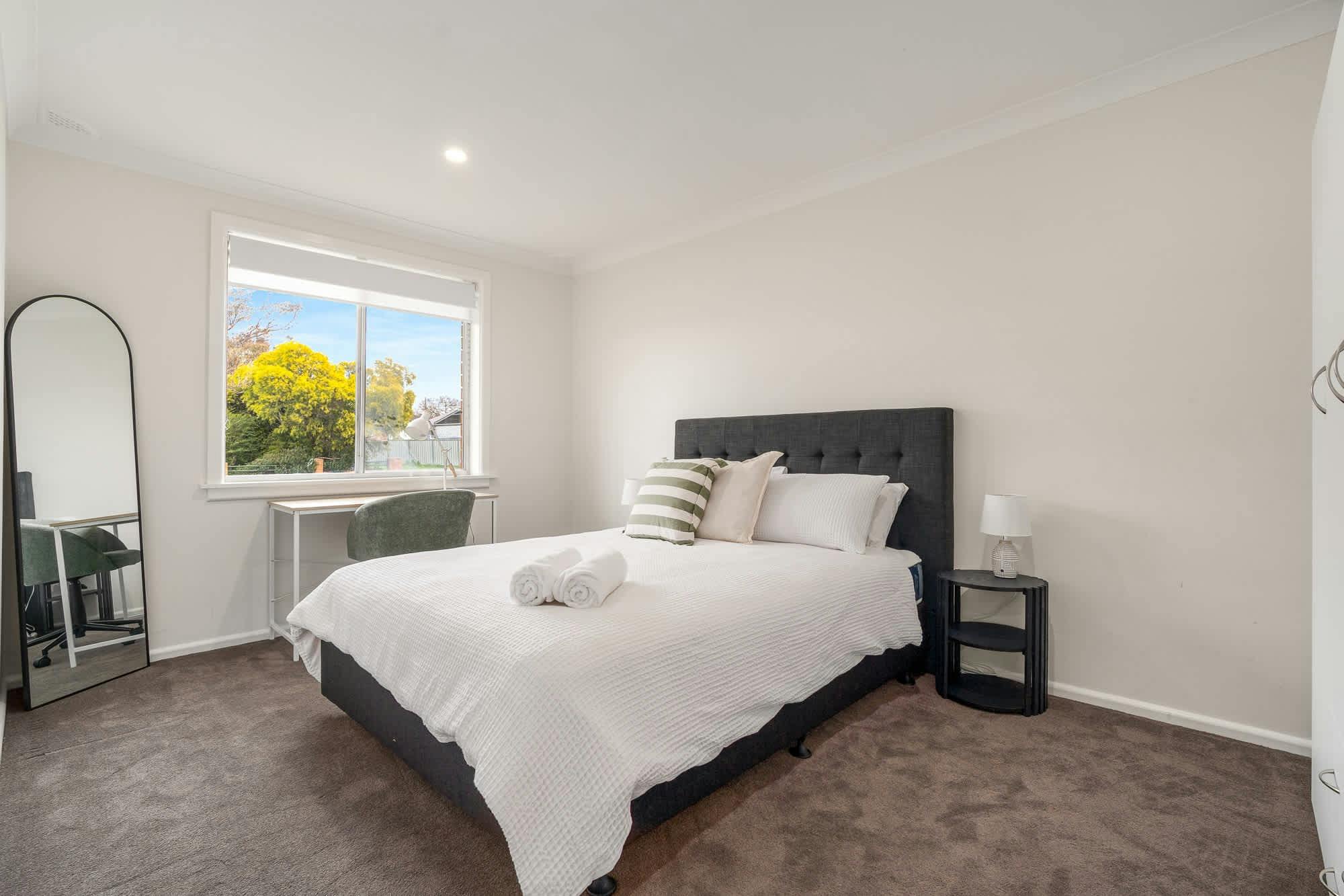 Large room with queen bed, desk and large mirror