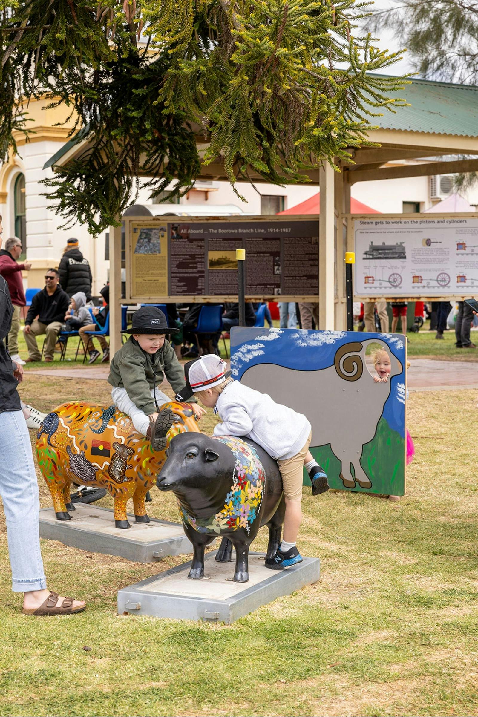 Children playing on painted stone sheep sculptures