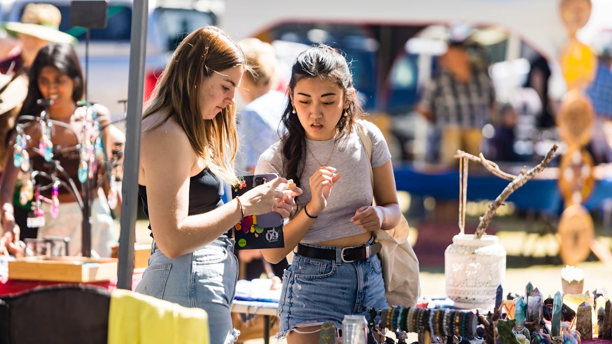 two young women looking at market items two young women looking at market items