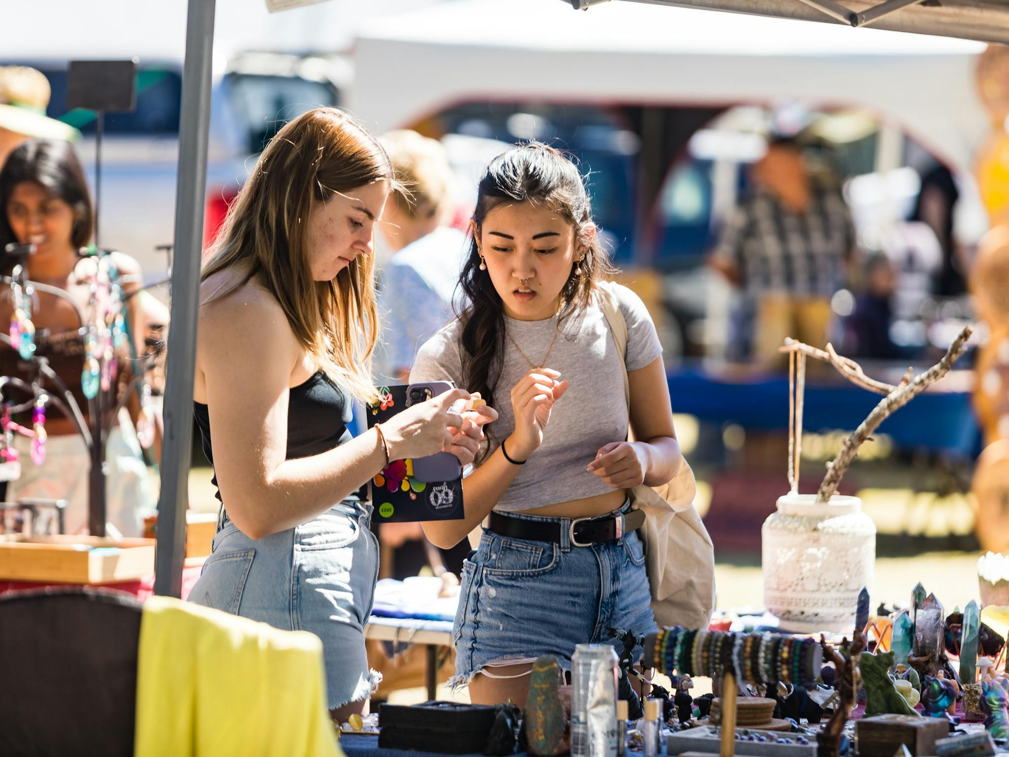two young women looking at market items two young women looking at market items