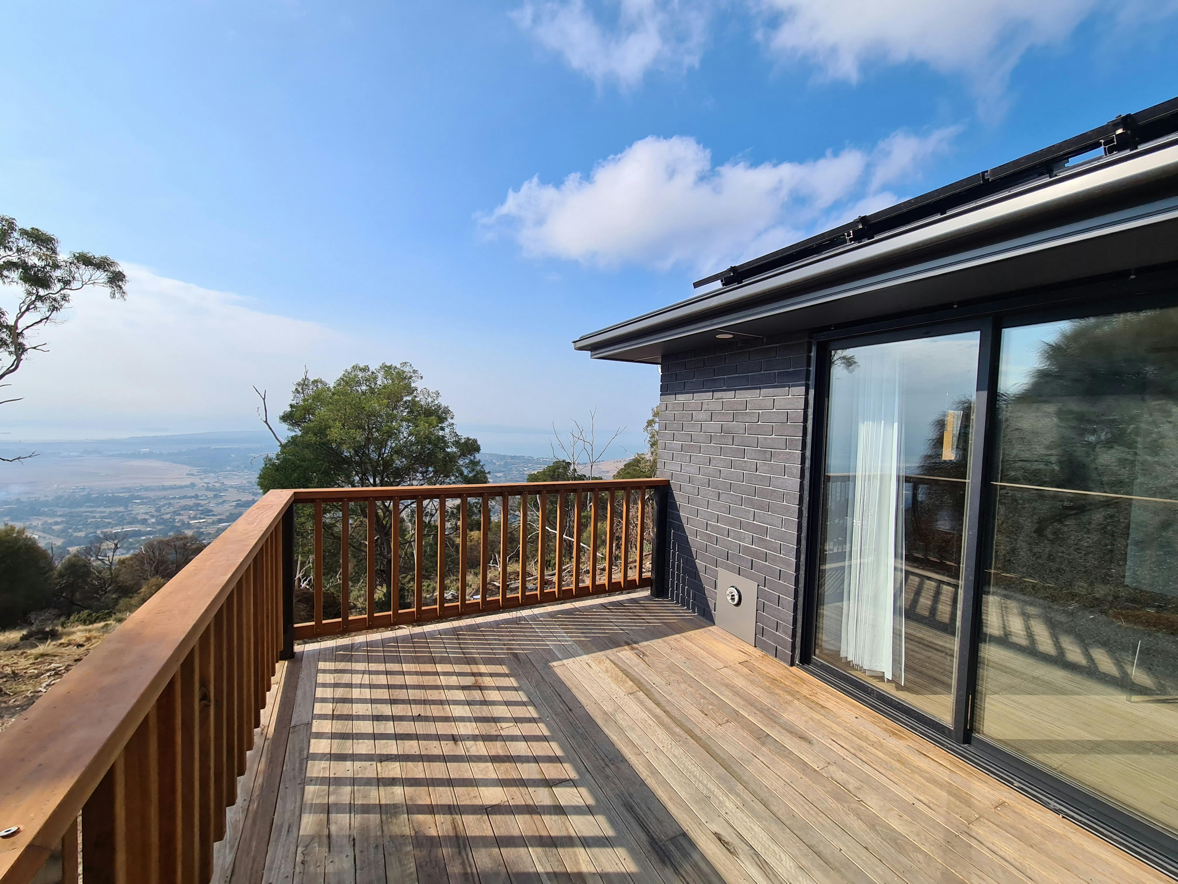 Wooden outdoor deck at Devil House overlooking the surrounding bushland and landscape