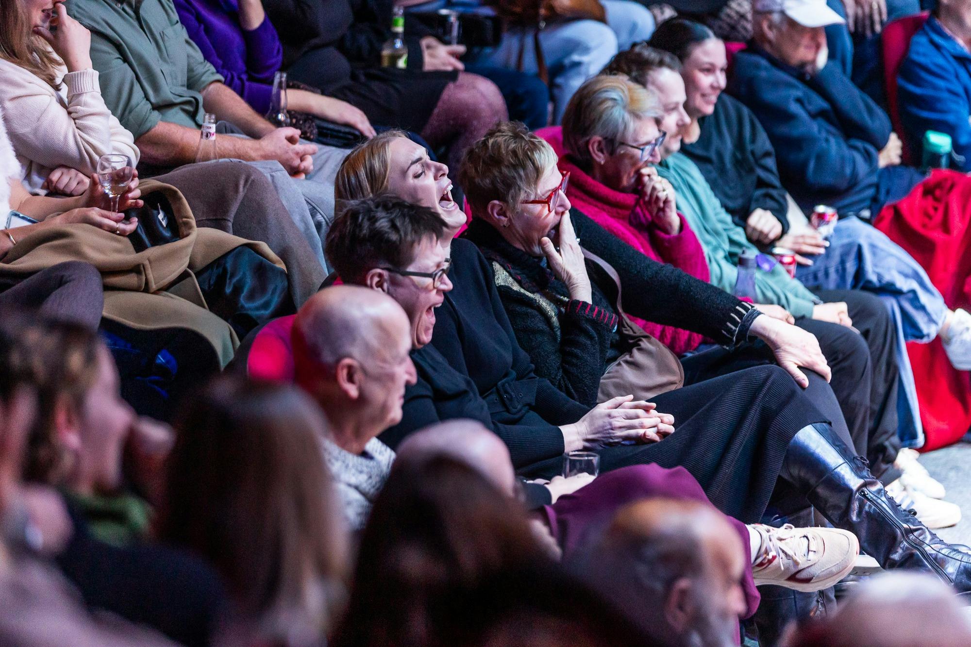 Audience for a comedian, laughing histerically and pointing at the stage
