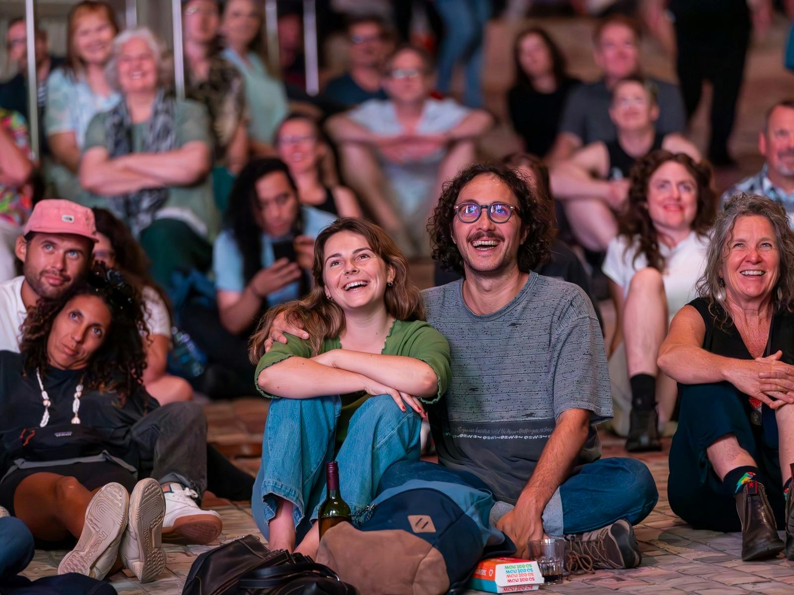 A man and woman smile while watching something off camera