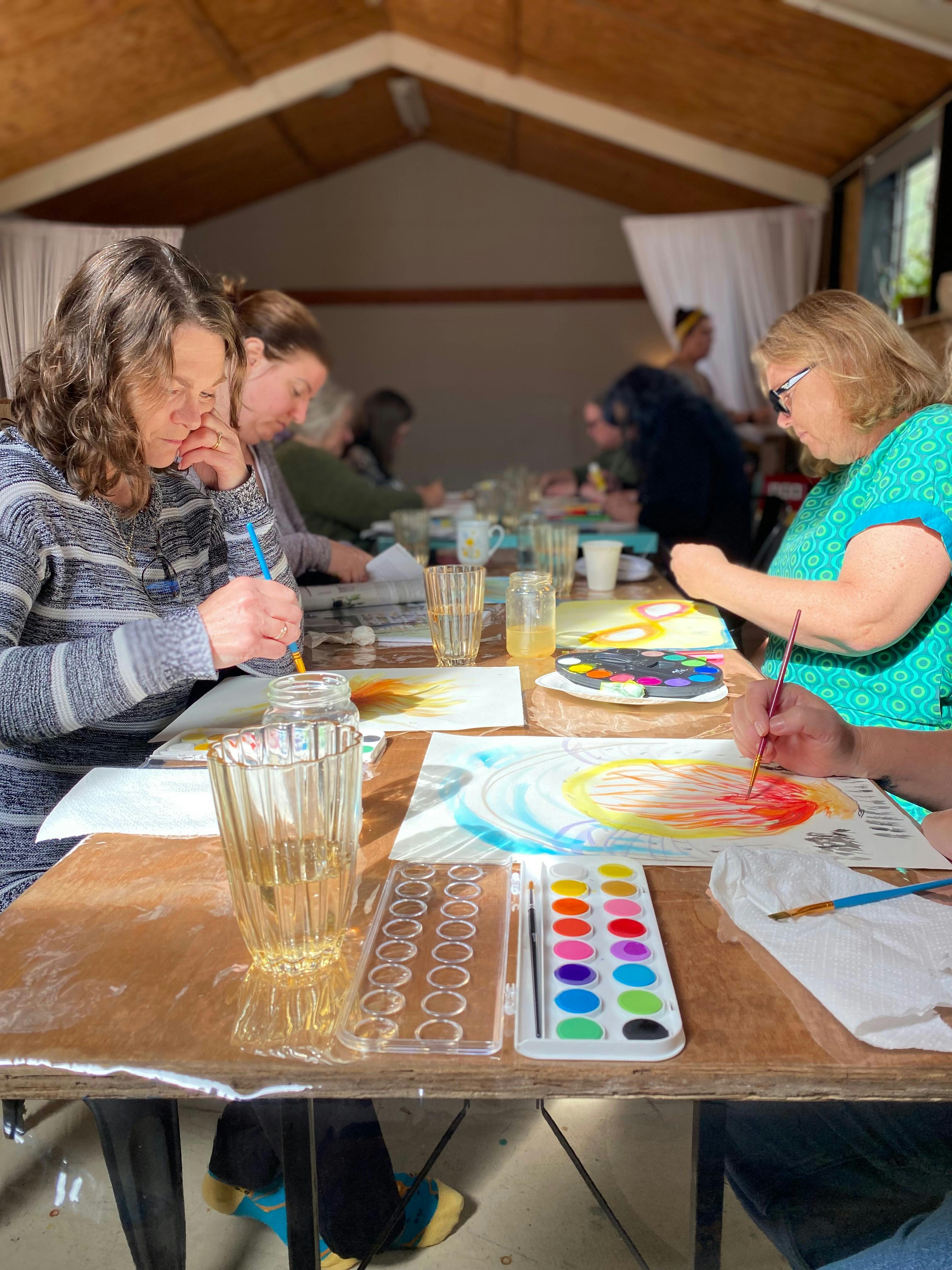 Women painting artwork at a table