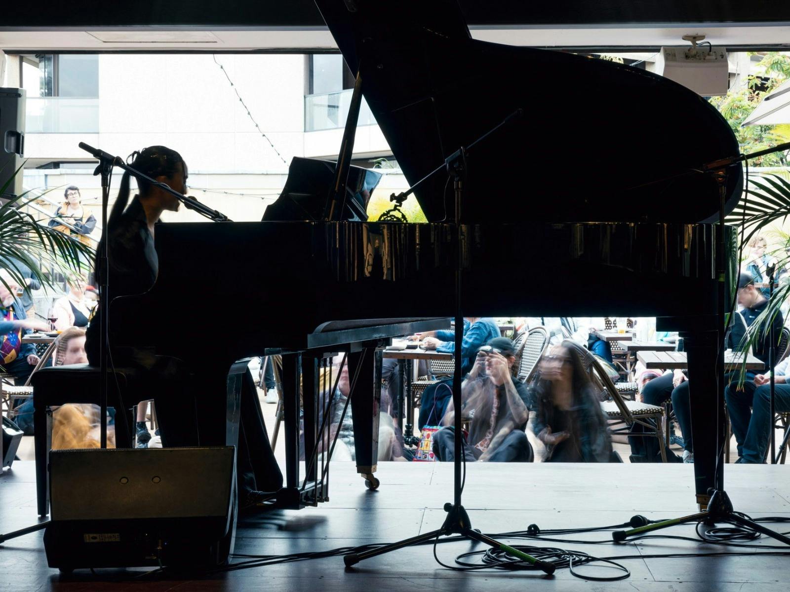 Silhouette of a female artist playing piano and singing on the Library Bar stage