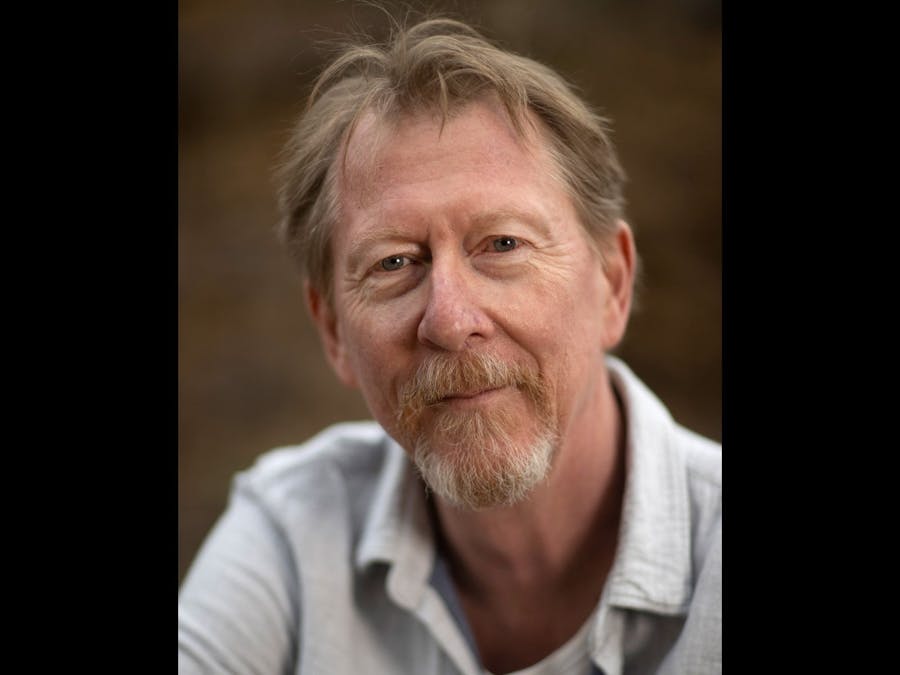 Man wearing a beige shirt, with short dark blonde hair and a beard