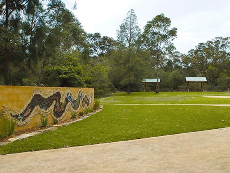 Community art mural at the entrance to Bomaderry Creek Regional Park with picnic shelters in the