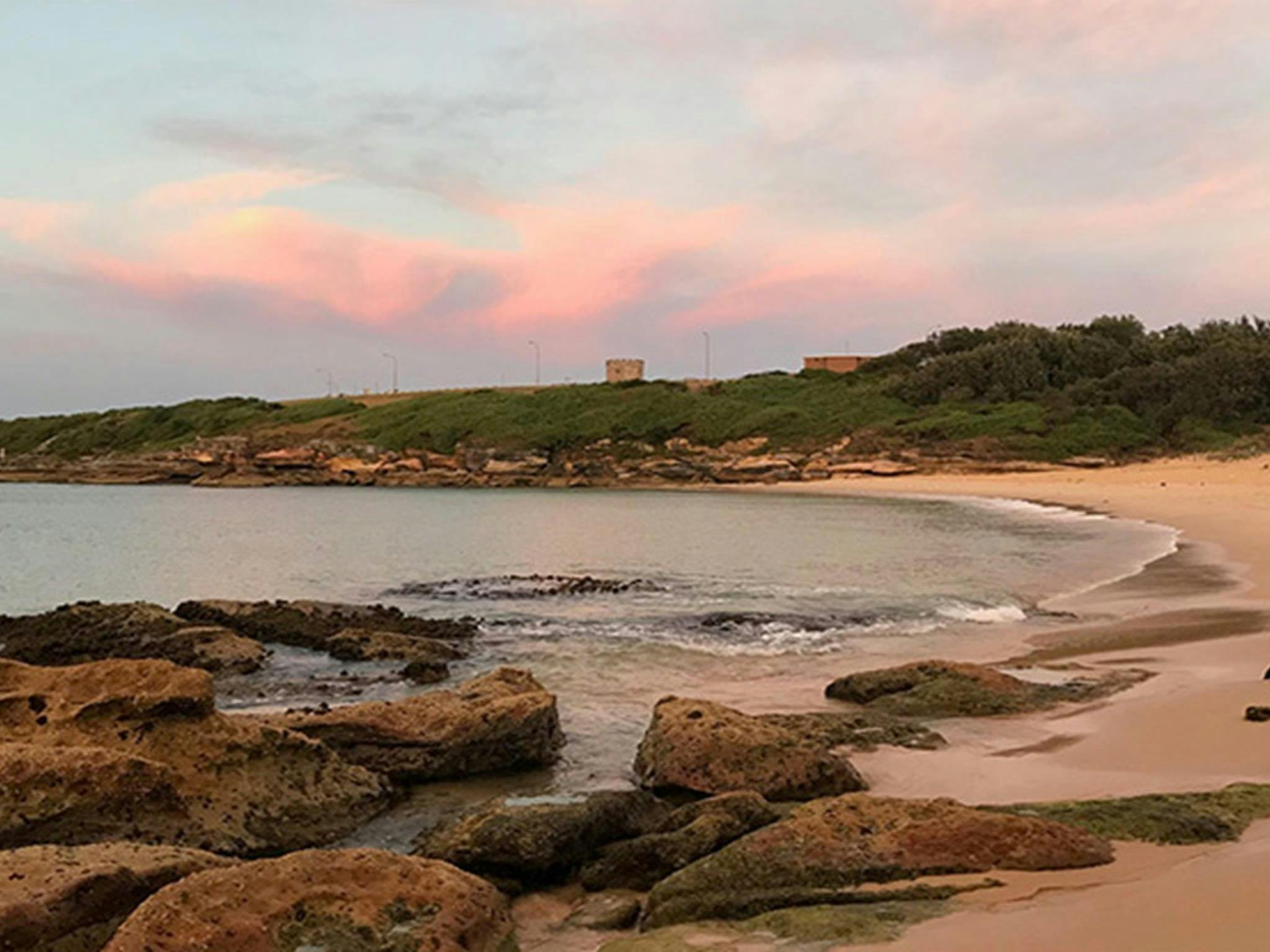 日出時的康旺海灘，背景是灌木叢和歷史悠久的塔樓。照片：斯泰西