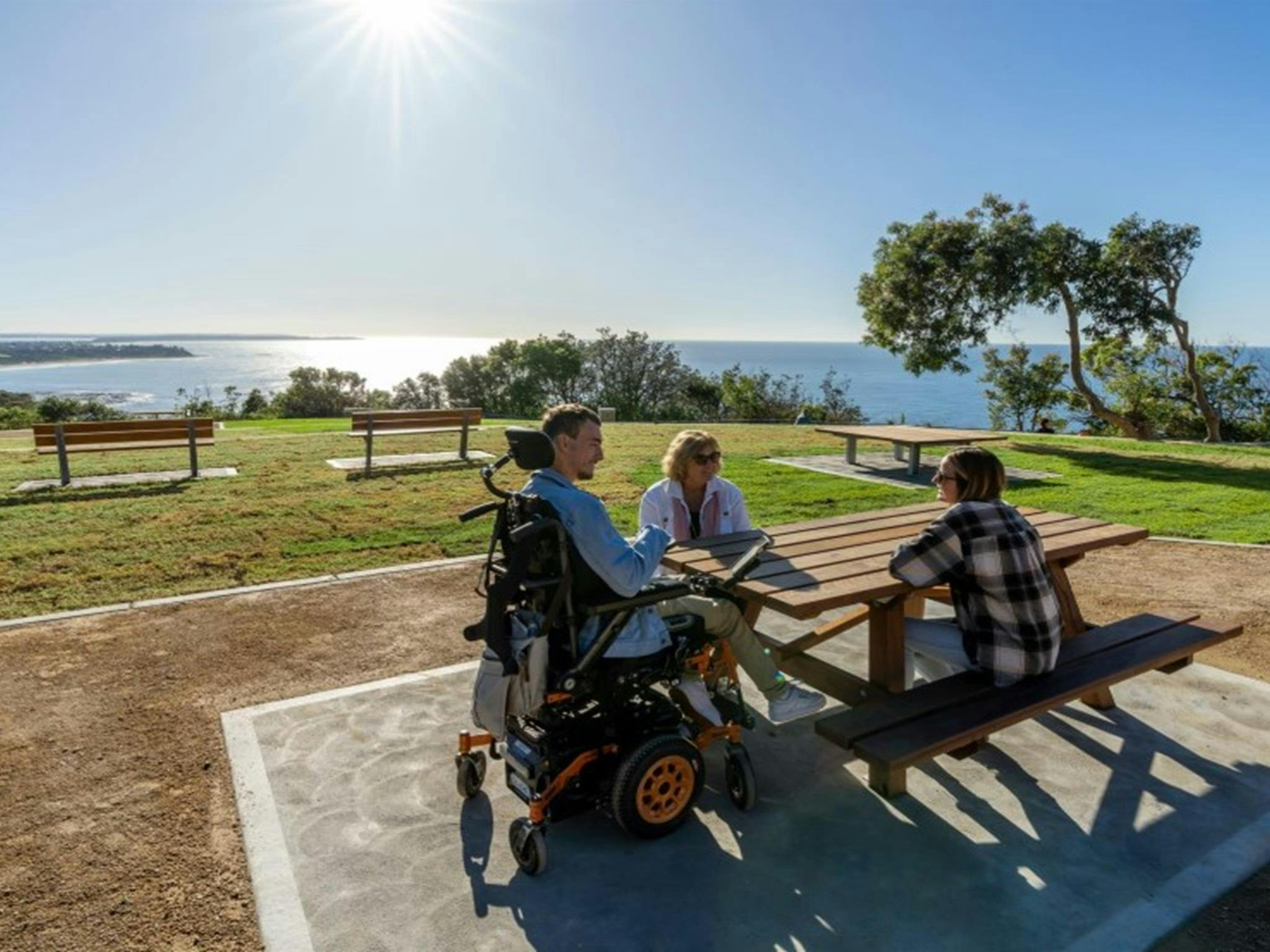 一群朋友在怀拉巴隆的克拉克内克角观景台的一张无障碍野餐桌旁。