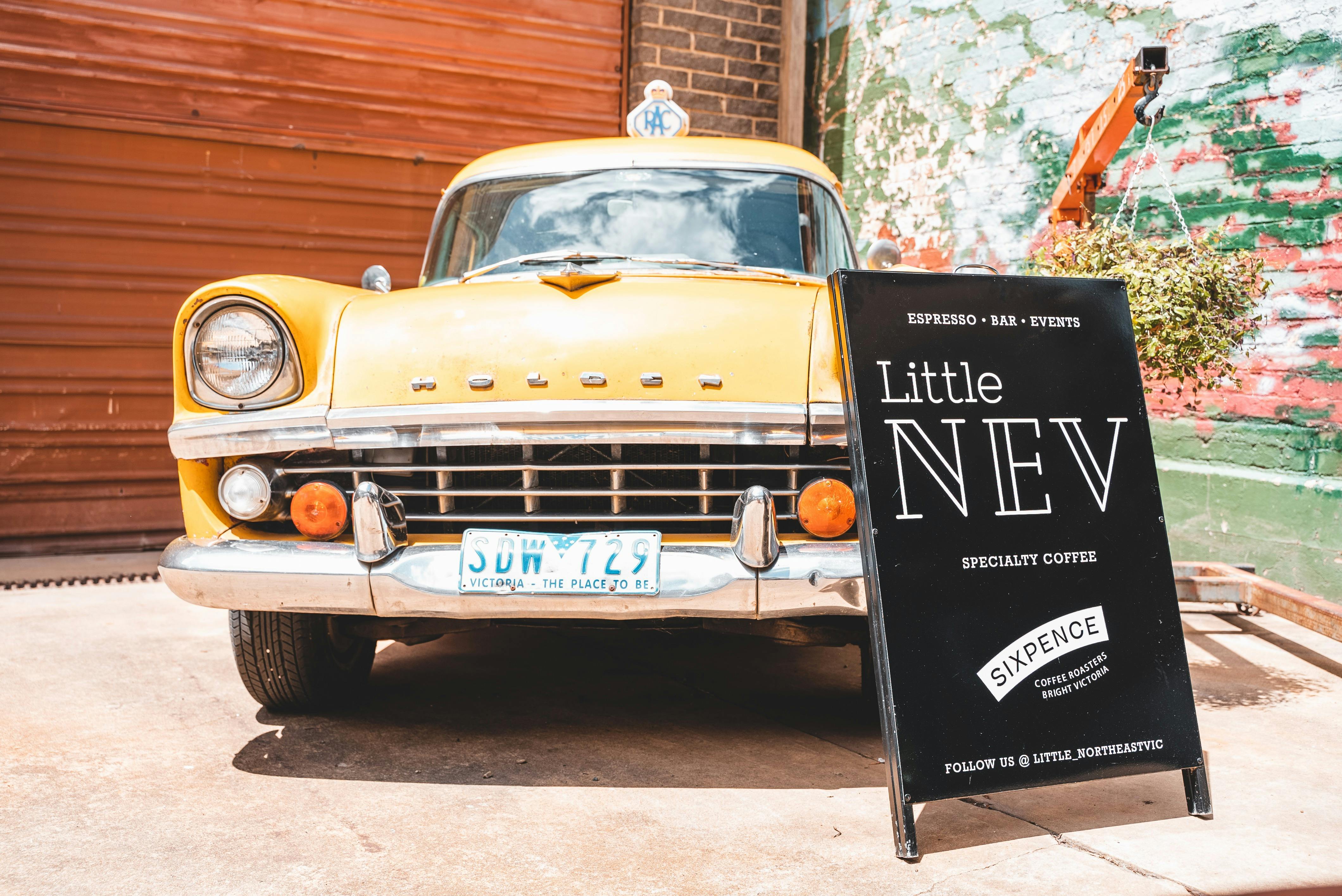 Close up shot of the yellow Holden FB RACV vehicle with the Little NEV sign.