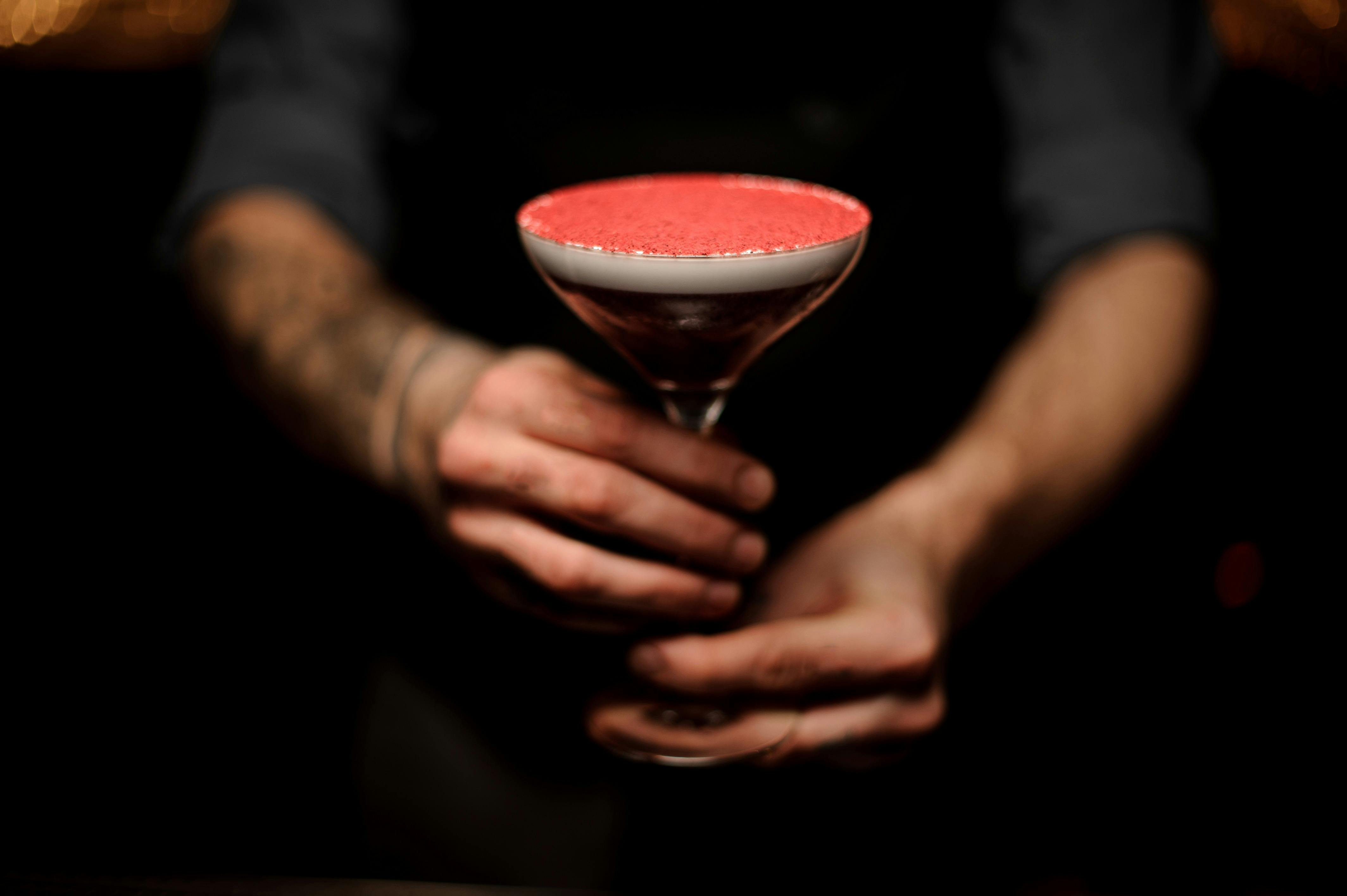 Close-up of tattooed bartender holding a cocktail