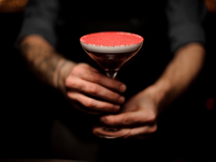 Close-up of tattooed bartender holding a cocktail