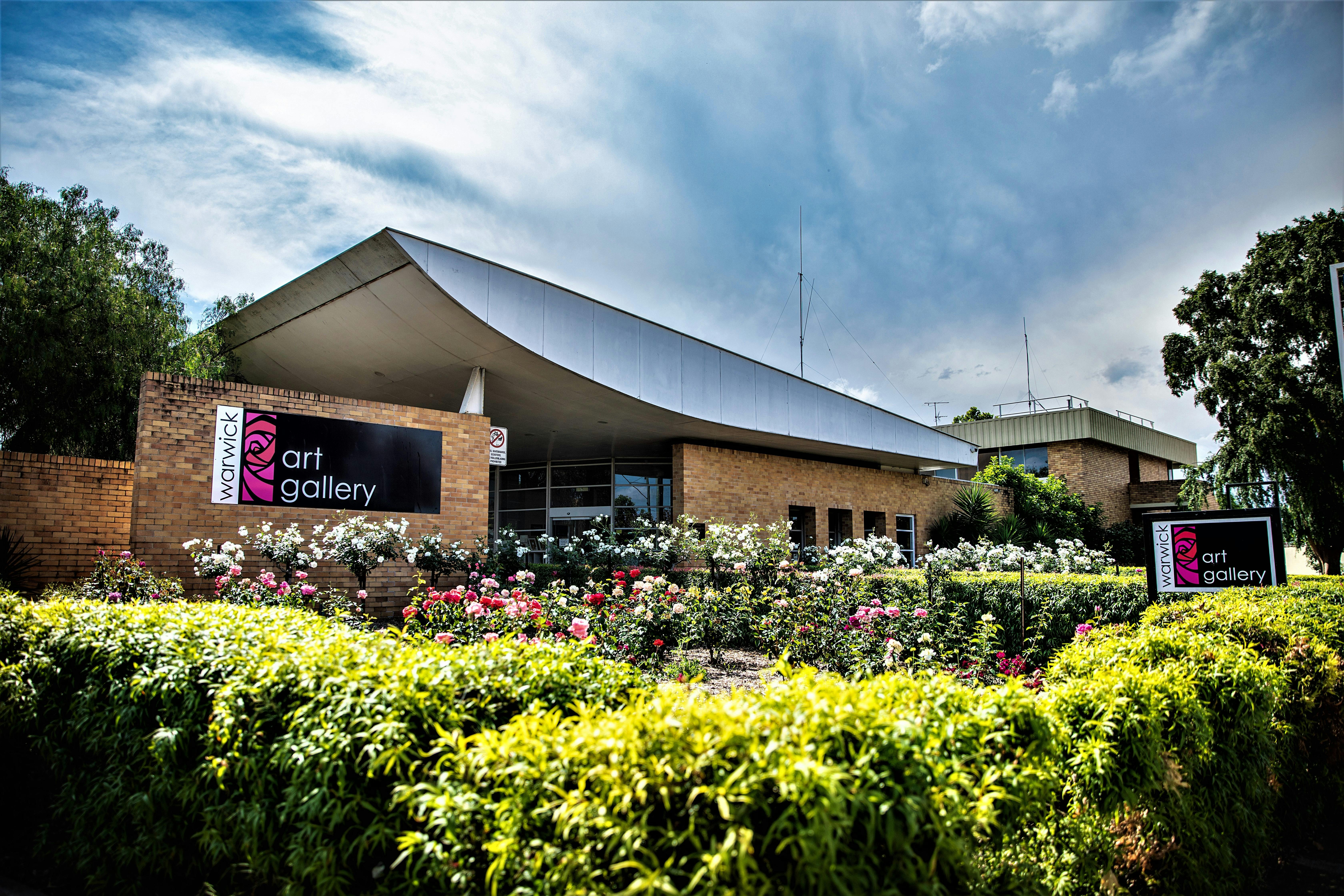 Exterior of Warwick Art Gallery, modern brick building with curved roof, surrounded by a rose garden