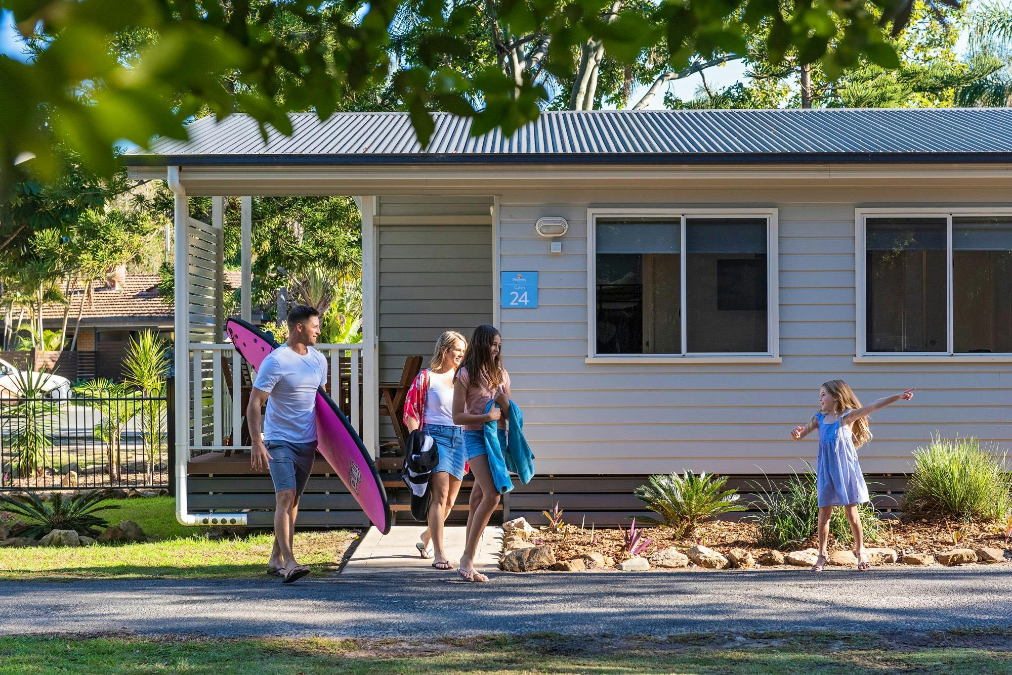 Family outside of a cabin at Discovery Parks - Emerald Beach