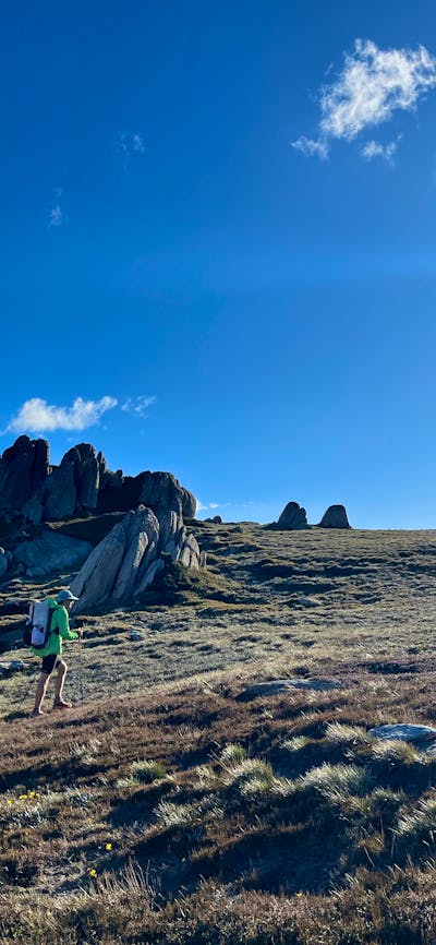 A hiker walking up a slope off track.