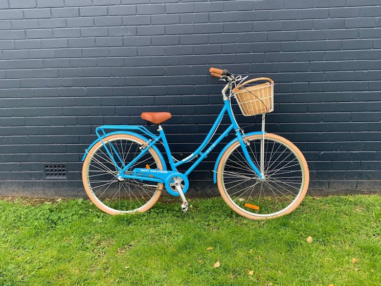 Vintage-style blue cruiser bike against dark blue brick wall.