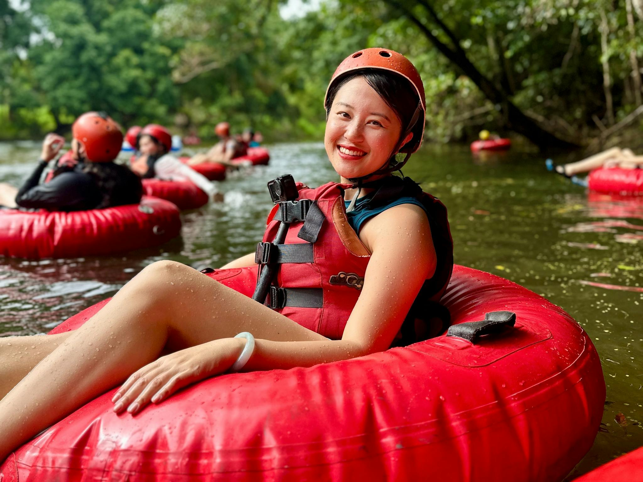 Woman in red tube and safety gear posed smiling at the camera as she floats down the Little Mulgrave Woman in red tube and safety gear posed smiling at the camera as she floats down the Little Mulgrave
