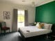 Queen bed and a single bed in a room with a green wall