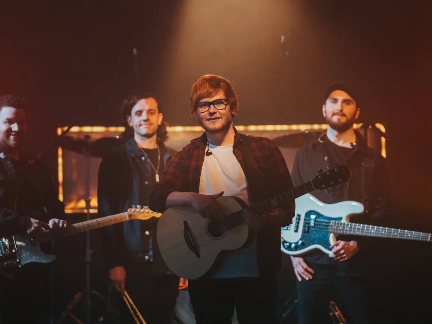 Band members stood in a dim orange light on stage