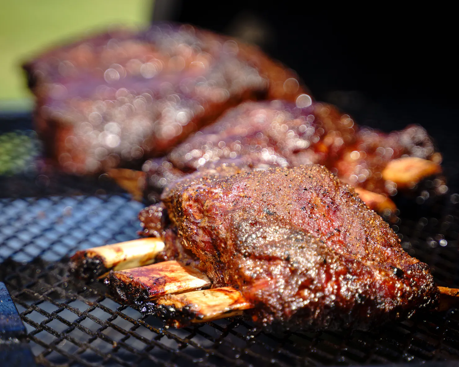 Authentic Low and Slow BBQ Ribs at Meat Noosa – Glazed, smoky ribs sizzling on the grill, ready to b
