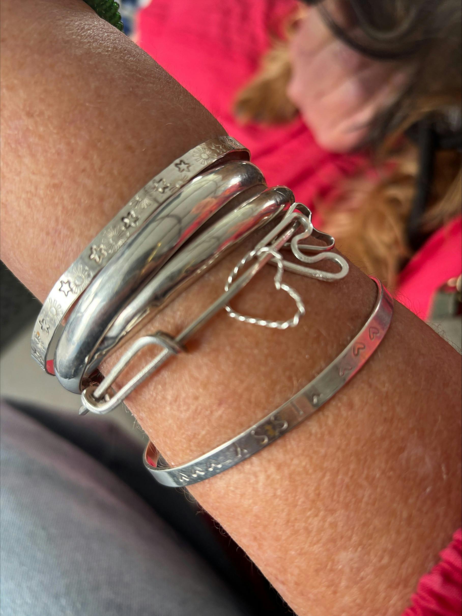 Woman's wrist displaying hand-made bangles and braclets made of silver