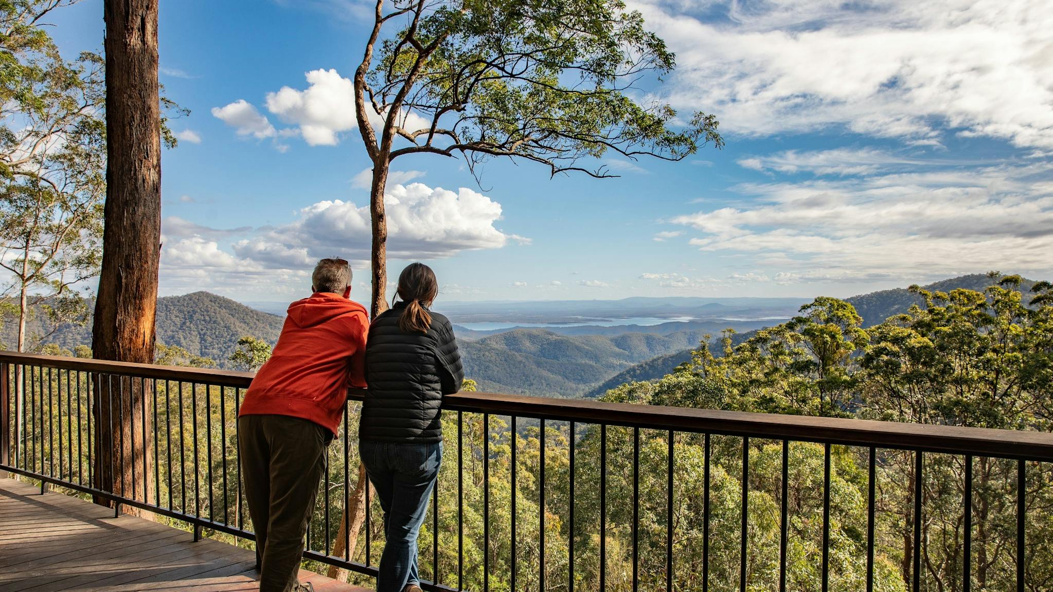 A middle aged couple leaning on a Lookout guardrail viewing the mountain ranges