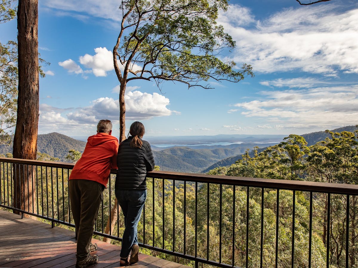 A middle aged couple leaning on a Lookout guardrail viewing the mountain ranges