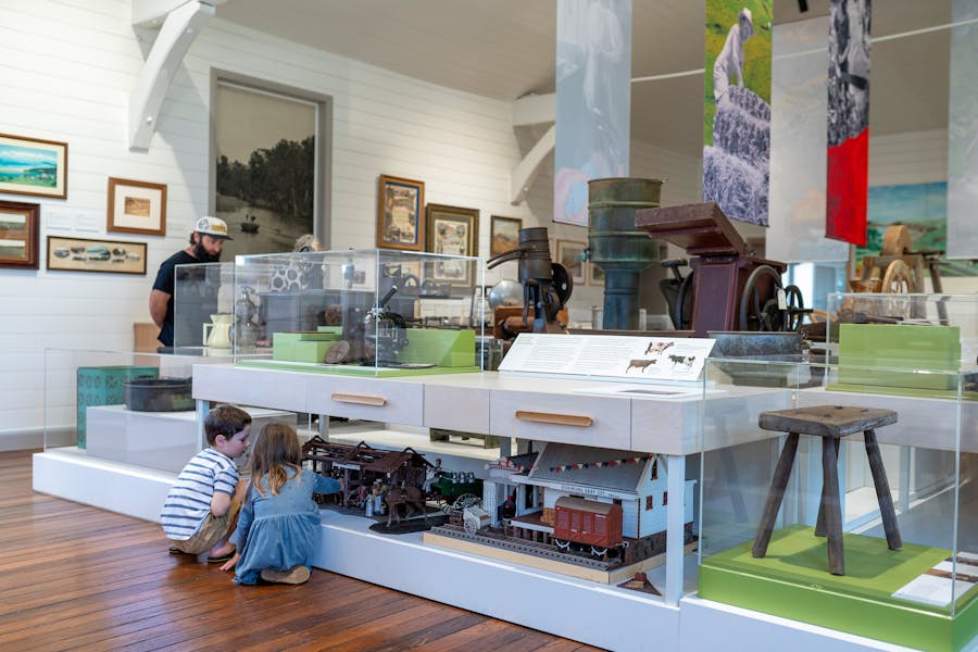 Two children looking at models of buildings. Above them are a number of historical objects.