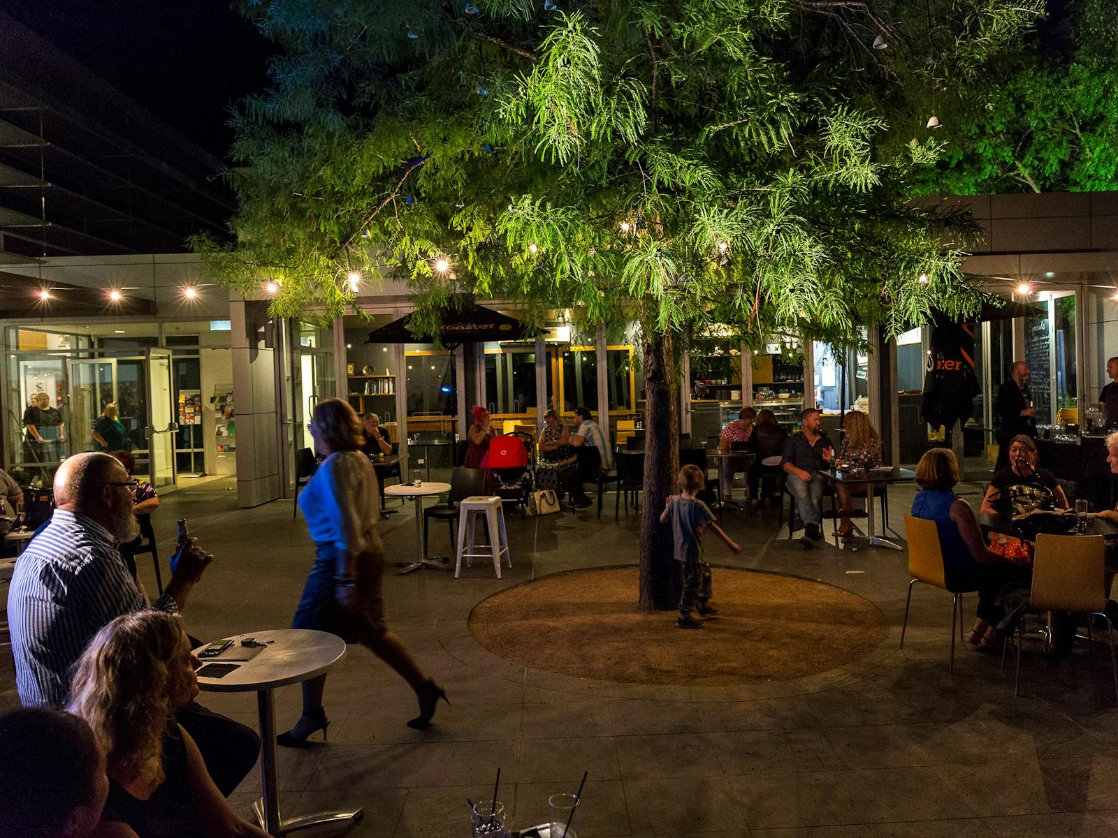 People eating and drinking in outdoor courtyard on summer evening